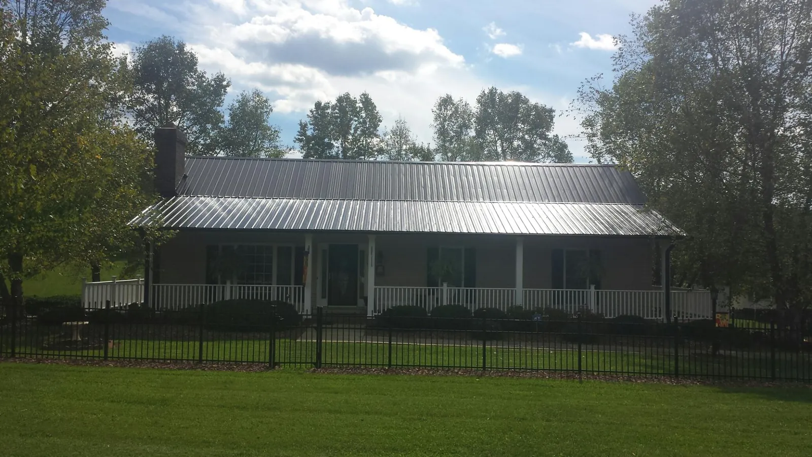 Gray metal roof on a brick ranch with a full width front porch — Gutter Guard Installation work by our crew in Bucyrus